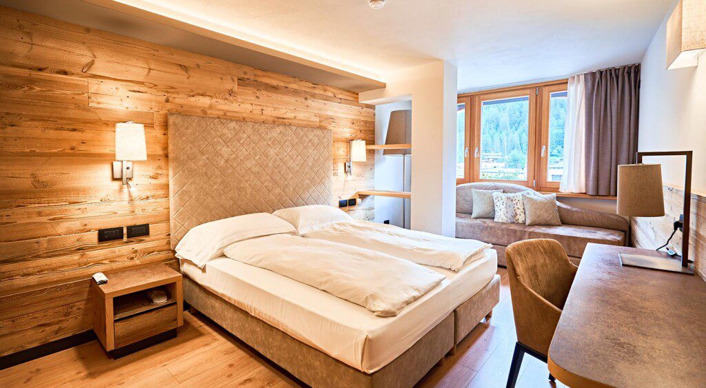 A cozy hotel room with a wooden accent wall, a large bed, and a seating area by the window.