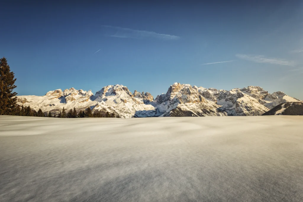 Distesa di neve intatta davanti alle Dolomiti di Brenta illuminate dal sole