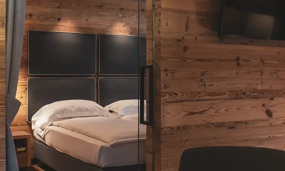 Interno di una camera da letto con pareti in legno e un letto matrimoniale.