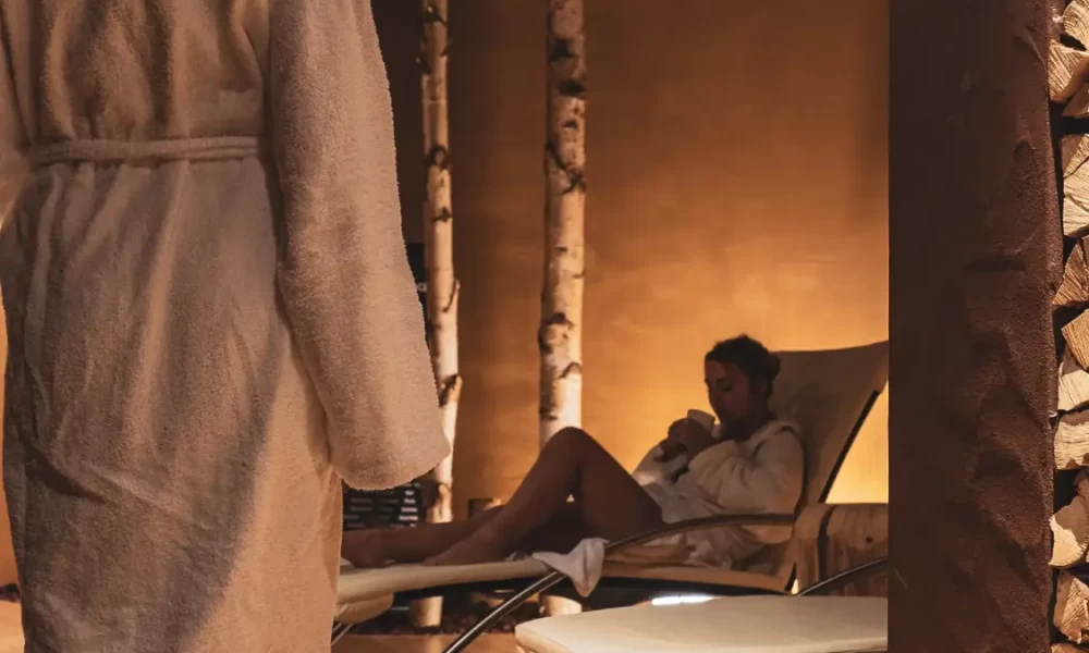 Two people in robes relaxing in a cozy, dimly lit spa room.