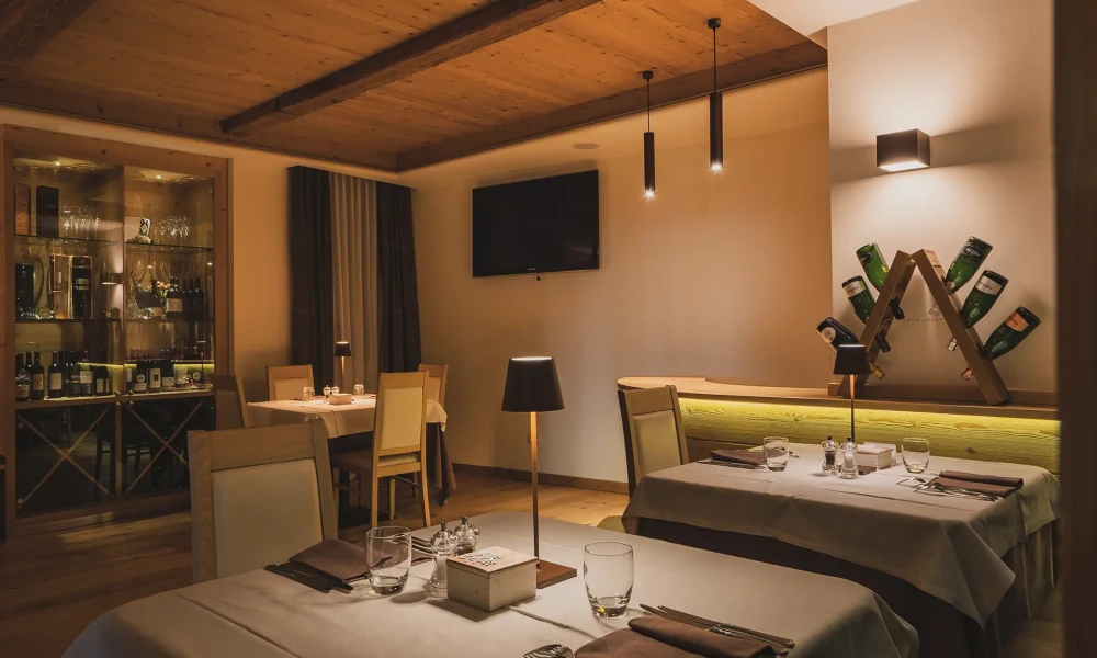 Interno di un ristorante elegante con tavoli apparecchiati e illuminazione soffusa.