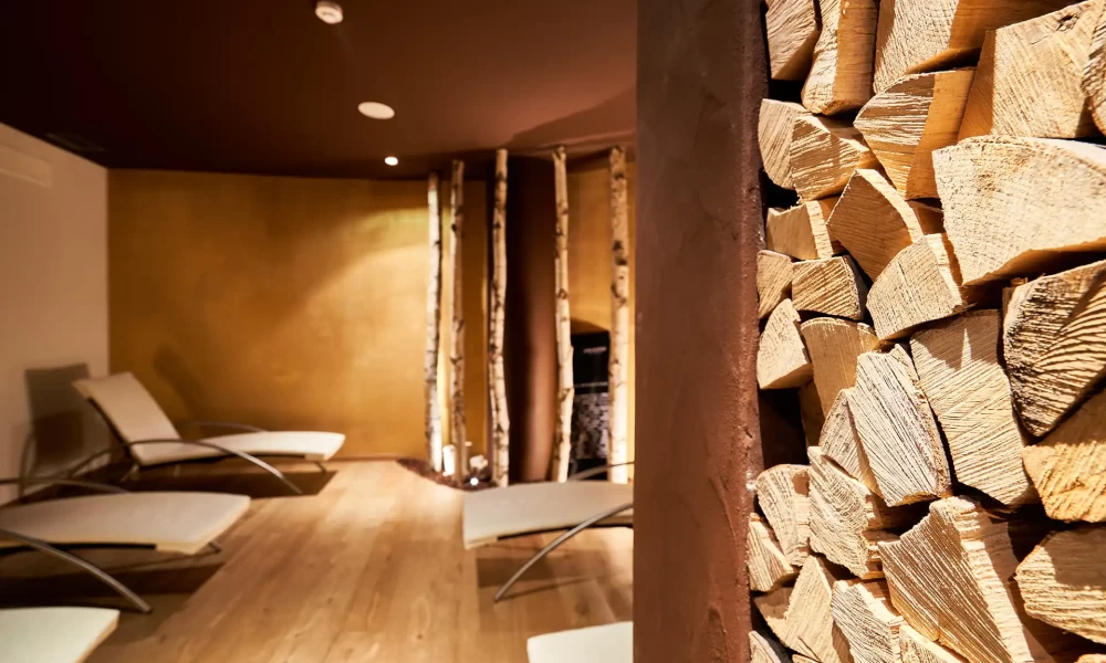 A relaxing spa room with stacked firewood and lounge chairs.