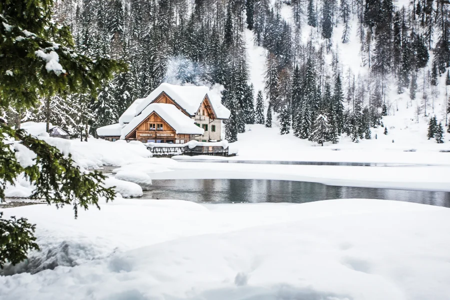 Rifugio innevato in riva al Lago Nambino tra gli abeti, a Madonna di Campiglio