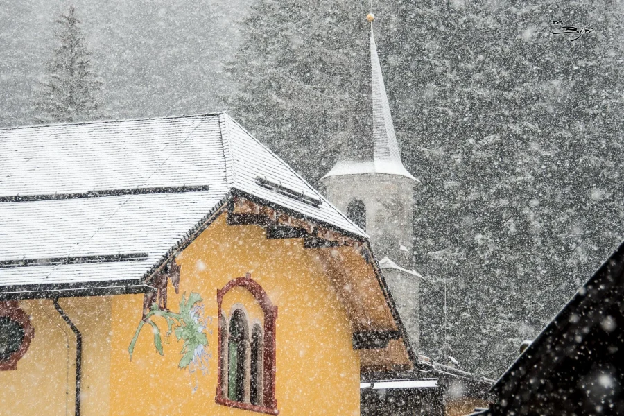 Nevicata sulla chiesa di Madonna di Campiglio con il campanile tra gli abeti