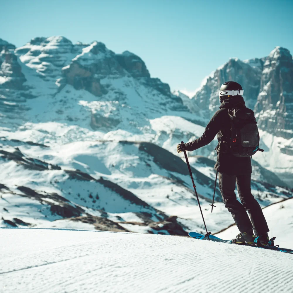 Sciatore fermo su una pista battuta con le Dolomiti di Brenta sullo sfondo