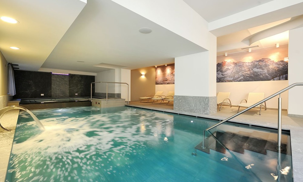 Indoor pool area with lounge chairs and mountain mural.